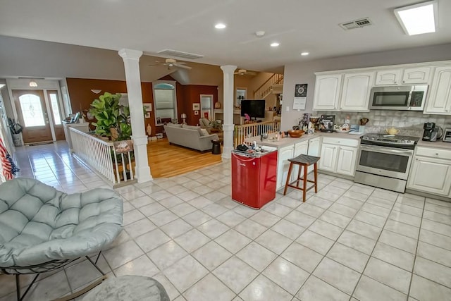 kitchen featuring kitchen peninsula, a kitchen bar, stainless steel appliances, ceiling fan, and white cabinetry