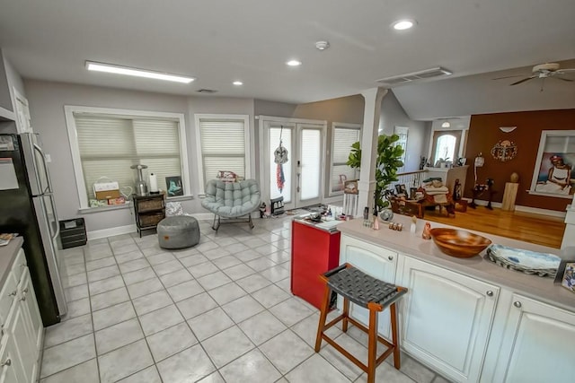 kitchen with light tile patterned floors, white cabinetry, a wealth of natural light, and stainless steel refrigerator