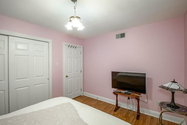 bedroom with a notable chandelier, light hardwood / wood-style floors, and a closet