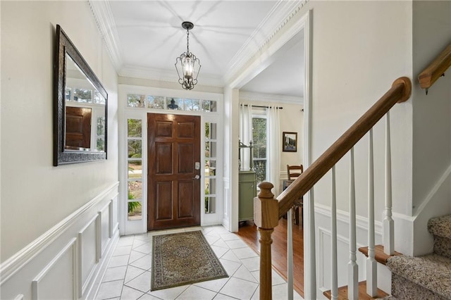 entrance foyer featuring light tile patterned floors, ornamental molding, and a chandelier