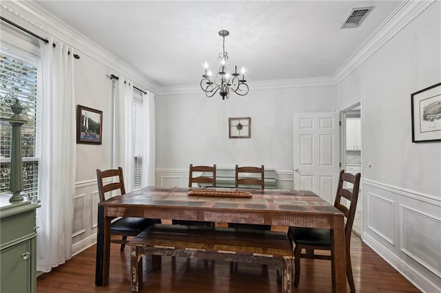 dining space featuring dark hardwood / wood-style flooring, ornamental molding, and an inviting chandelier