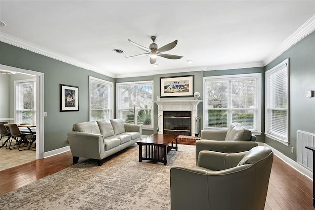 living room with hardwood / wood-style floors, a fireplace, ceiling fan, and crown molding