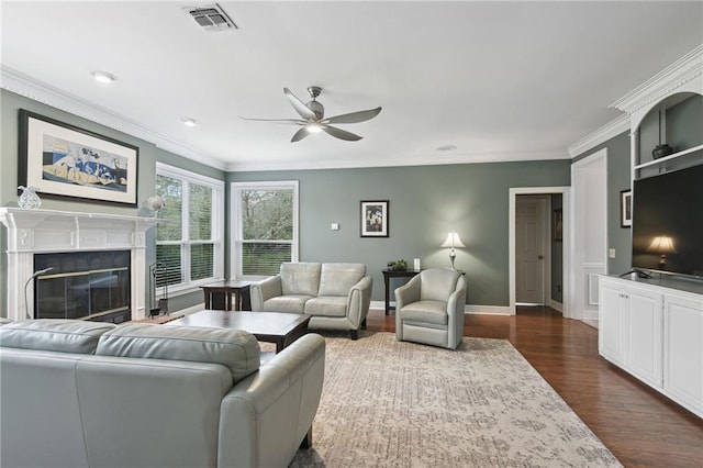 living room with dark hardwood / wood-style flooring, ceiling fan, ornamental molding, and a tiled fireplace