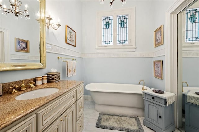 bathroom with vanity, a bath, and an inviting chandelier