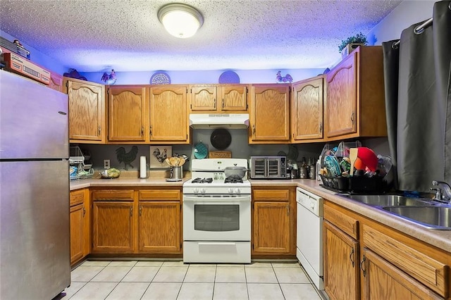 kitchen featuring a textured ceiling, light tile patterned floors, sink, and white appliances