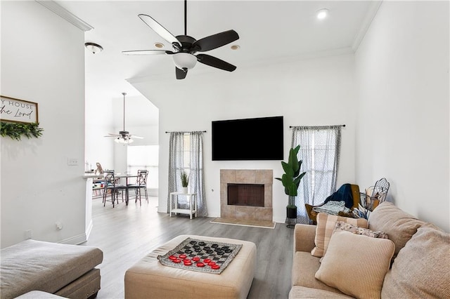 living room with ceiling fan, a fireplace, ornamental molding, and hardwood / wood-style floors