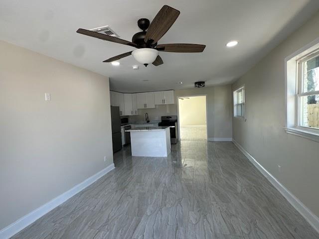 kitchen with ceiling fan, sink, a kitchen island, white cabinets, and appliances with stainless steel finishes