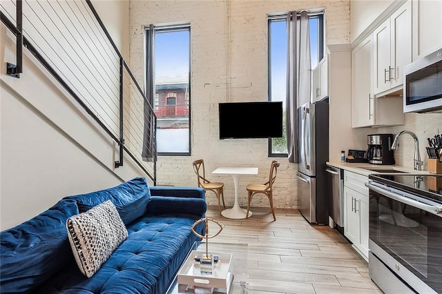 living room featuring plenty of natural light, light hardwood / wood-style floors, and brick wall