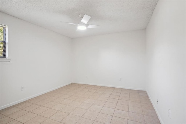 spare room featuring ceiling fan, light tile patterned flooring, and a textured ceiling