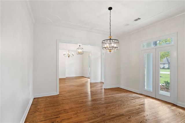 unfurnished dining area featuring hardwood / wood-style flooring, a notable chandelier, ornamental molding, and french doors