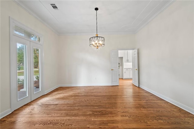 empty room with wood-type flooring, an inviting chandelier, and ornamental molding