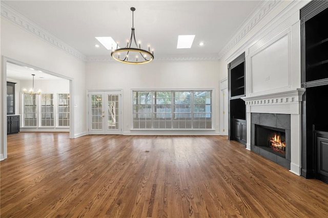 unfurnished living room featuring a tiled fireplace, a skylight, dark wood-type flooring, and ornamental molding