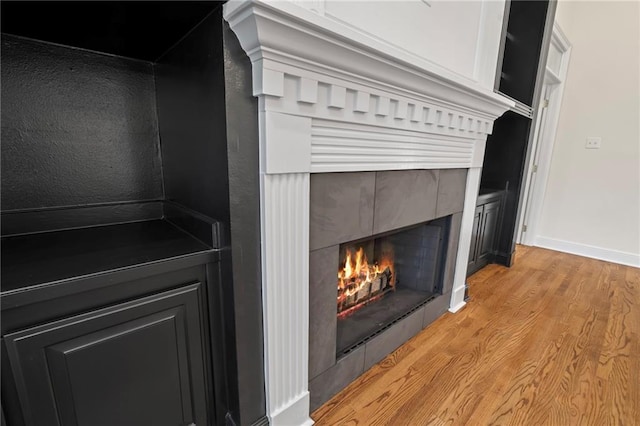 room details featuring a tile fireplace and wood-type flooring