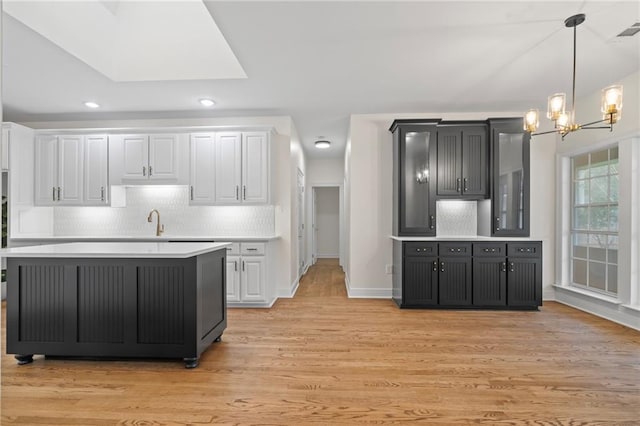 kitchen featuring white cabinets, a chandelier, and light wood-type flooring