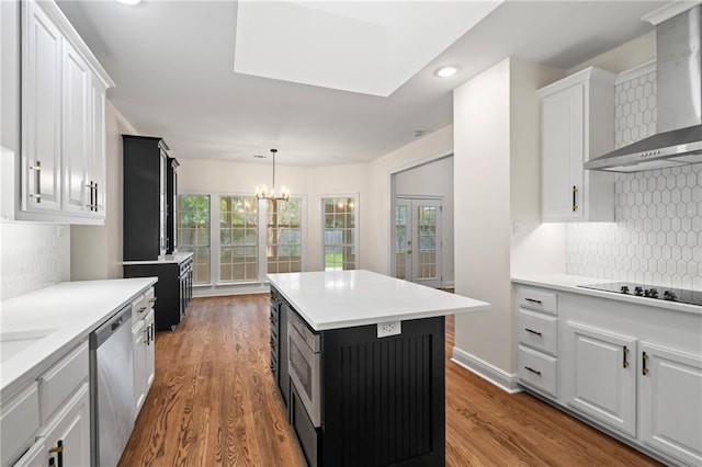 kitchen with white cabinetry, wall chimney exhaust hood, hardwood / wood-style flooring, and a kitchen island