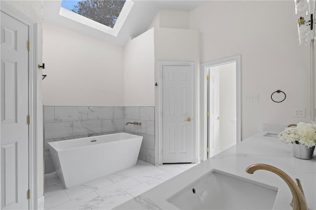 bathroom featuring vanity, lofted ceiling with skylight, a tub, and tile walls