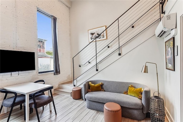 living area featuring an AC wall unit, stairs, wood finished floors, and a healthy amount of sunlight