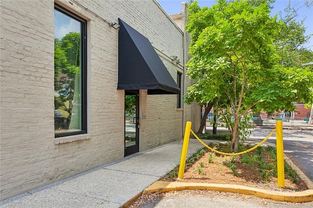 view of property exterior featuring brick siding and fence