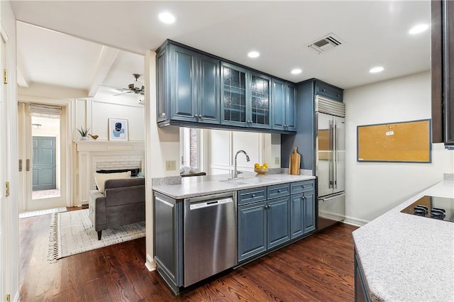 kitchen with stainless steel appliances, blue cabinets, dark wood-type flooring, and sink