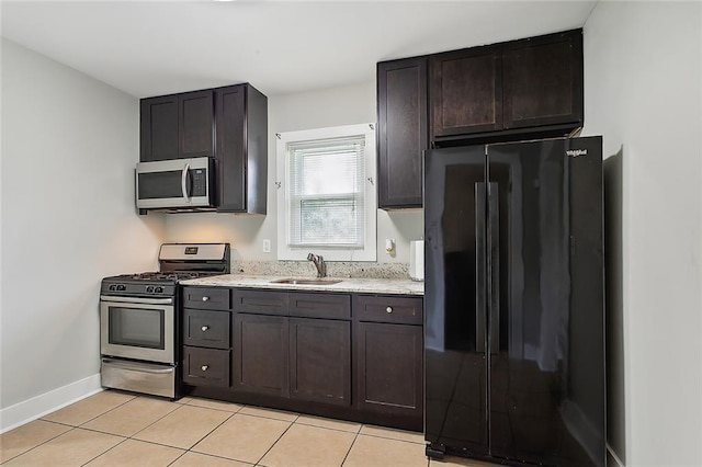 kitchen featuring appliances with stainless steel finishes, dark brown cabinetry, light tile patterned floors, and sink