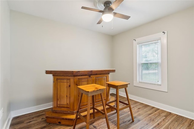 dining space featuring dark hardwood / wood-style floors, ceiling fan, and indoor bar