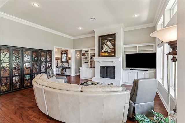 living room with crown molding, a brick fireplace, dark hardwood / wood-style floors, and built in shelves