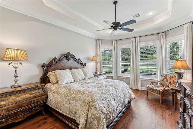 bedroom featuring dark wood-type flooring, ceiling fan, a tray ceiling, and multiple windows