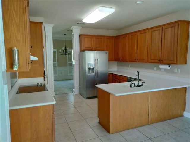 kitchen featuring a peninsula, brown cabinetry, stainless steel fridge, and a sink