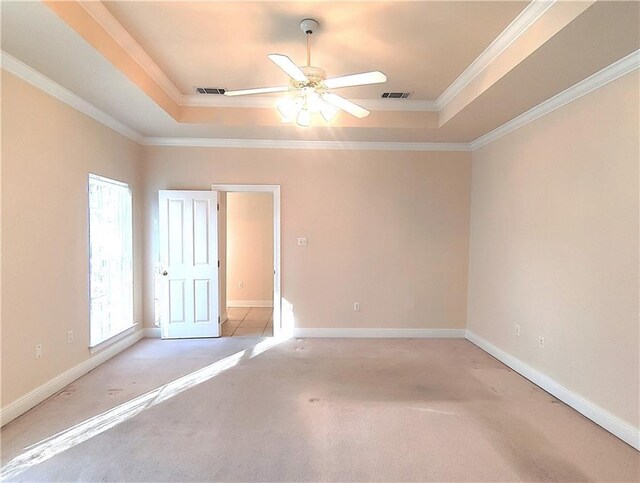 carpeted empty room with a raised ceiling, ceiling fan, and crown molding