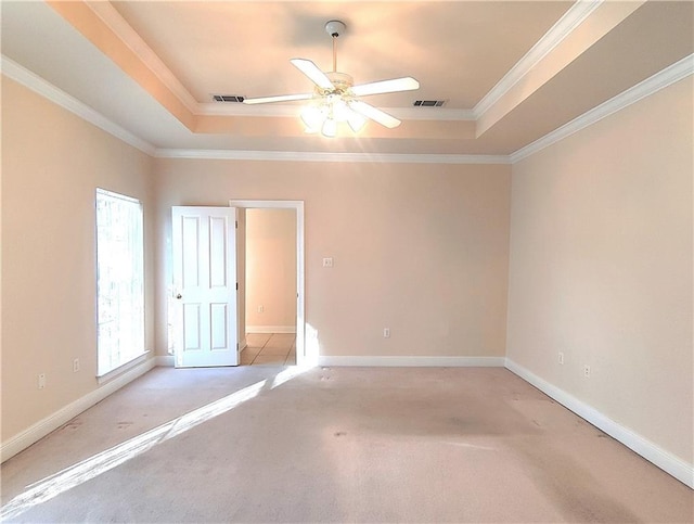 spare room with visible vents, a tray ceiling, and light colored carpet