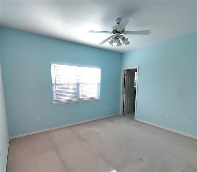 carpeted empty room with baseboards and a ceiling fan