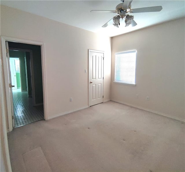 carpeted spare room with baseboards and a ceiling fan