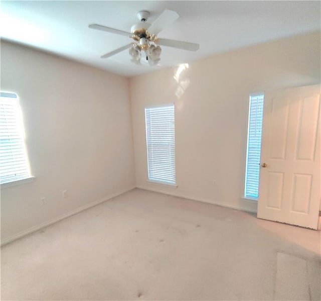 unfurnished room with baseboards, a ceiling fan, and light carpet