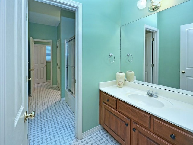 bathroom with vanity, baseboards, and enclosed tub / shower combo