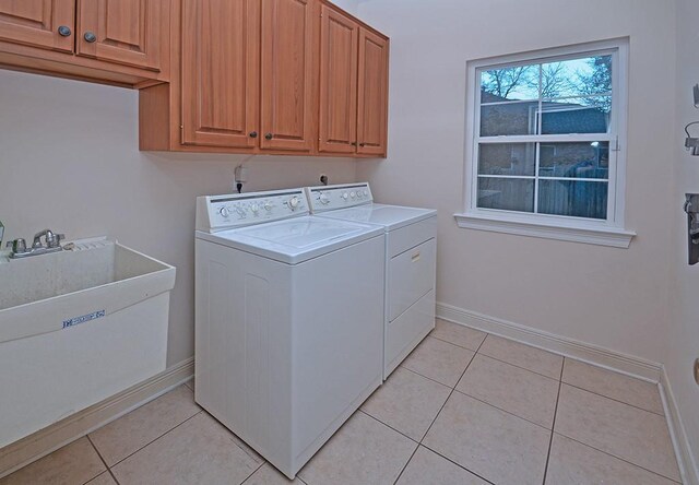 laundry room featuring washer and clothes dryer, sink, light tile patterned flooring, and cabinets