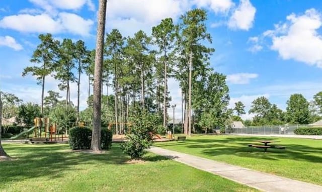 view of home's community featuring a lawn, fence, and playground community