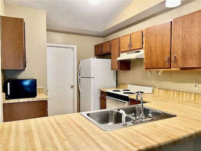 kitchen featuring a textured ceiling, white appliances, and sink