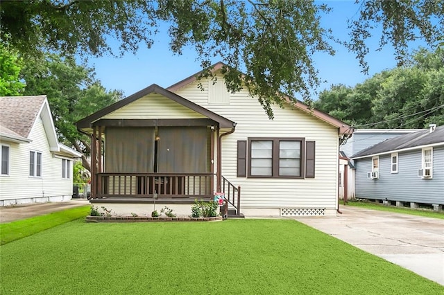 rear view of house featuring a lawn and a sunroom