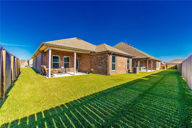 rear view of property featuring a yard, a patio, and central AC unit