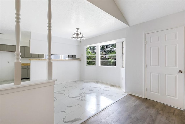 foyer with hardwood / wood-style flooring, an inviting chandelier, a textured ceiling, and vaulted ceiling