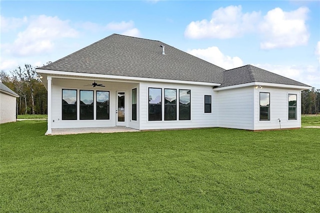 rear view of house with ceiling fan and a lawn