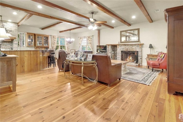 living room with a brick fireplace, ceiling fan, beamed ceiling, and light wood-type flooring