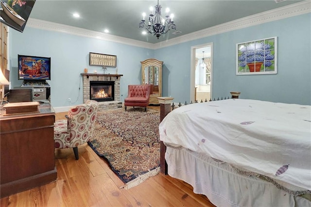 bedroom with ensuite bathroom, crown molding, a fireplace, a notable chandelier, and light hardwood / wood-style floors