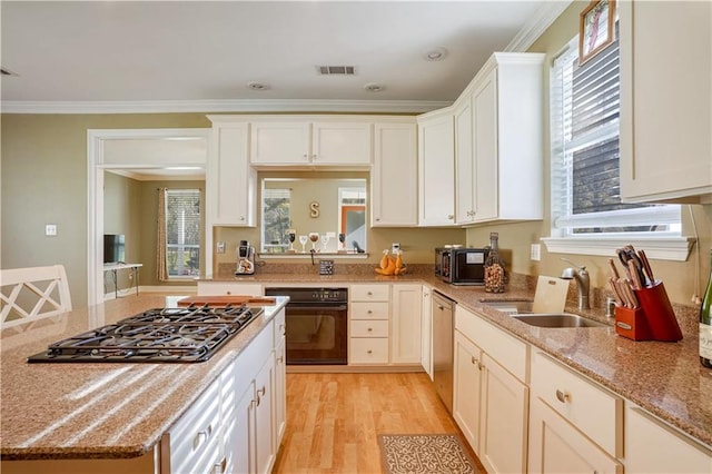 kitchen with sink, light wood-type flooring, ornamental molding, appliances with stainless steel finishes, and light stone counters