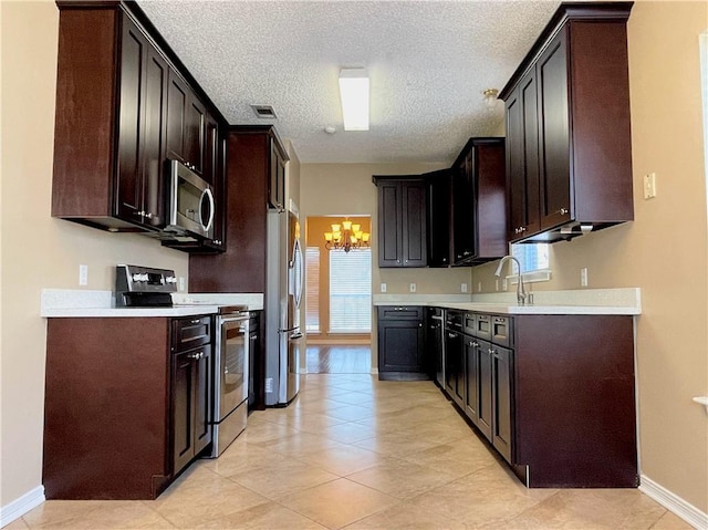 kitchen featuring a notable chandelier, a healthy amount of sunlight, dark brown cabinets, and stainless steel appliances