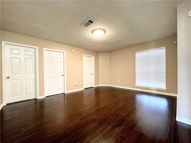 unfurnished bedroom with a textured ceiling and dark hardwood / wood-style flooring