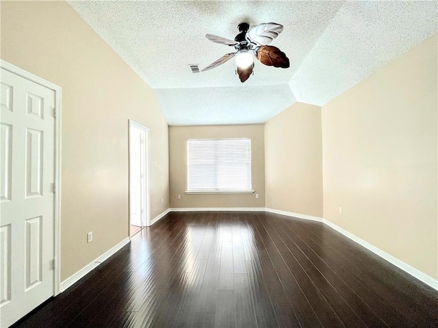 spare room with a textured ceiling, dark hardwood / wood-style flooring, vaulted ceiling, and ceiling fan