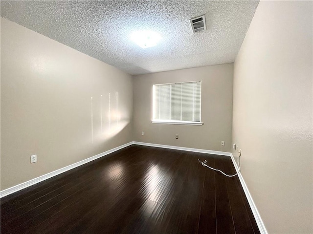 unfurnished room featuring dark hardwood / wood-style floors and a textured ceiling