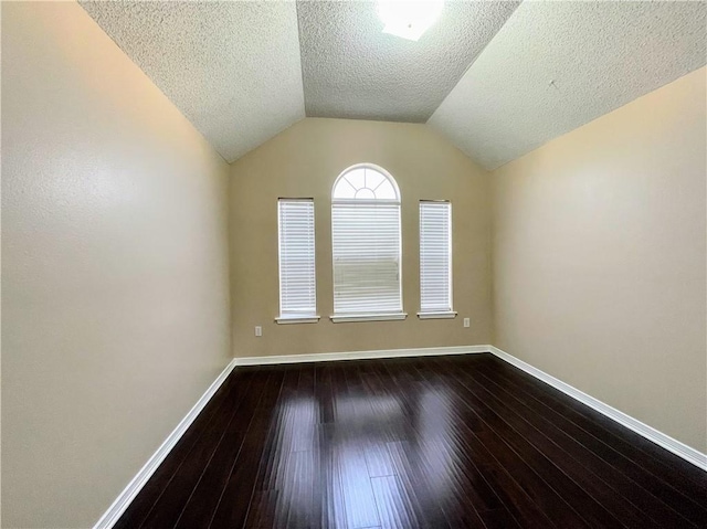 unfurnished room featuring a textured ceiling, dark hardwood / wood-style floors, and vaulted ceiling