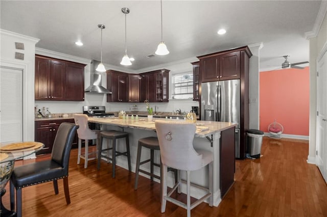 kitchen featuring wall chimney exhaust hood, ceiling fan, dark wood-type flooring, pendant lighting, and a center island